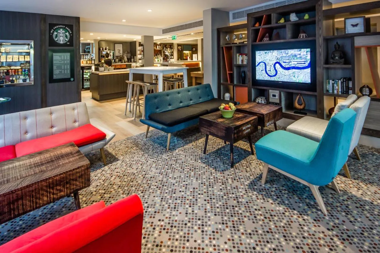 a living room with blue and red furniture and a tv at Holiday Inn London Camden Lock by IHG in London